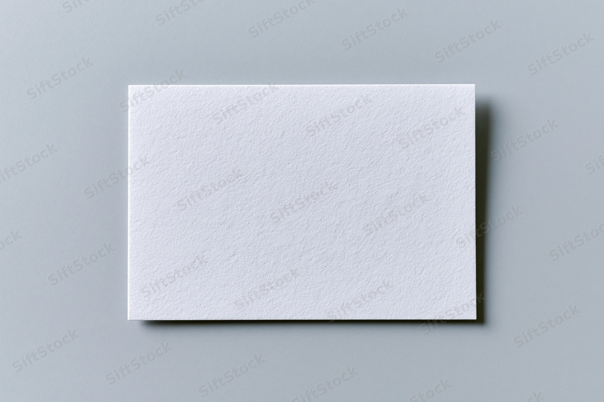 Blank white textured paper card centered on flat gray surface