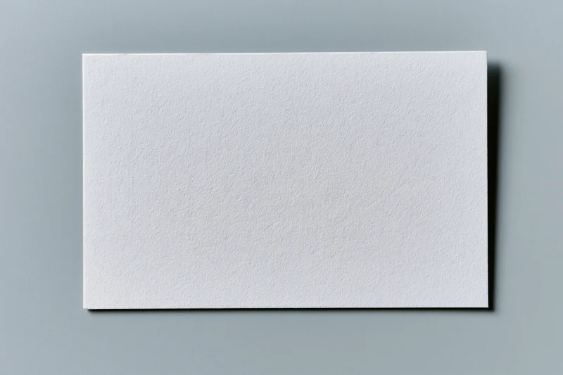 Blank white textured paper card centered on flat gray surface