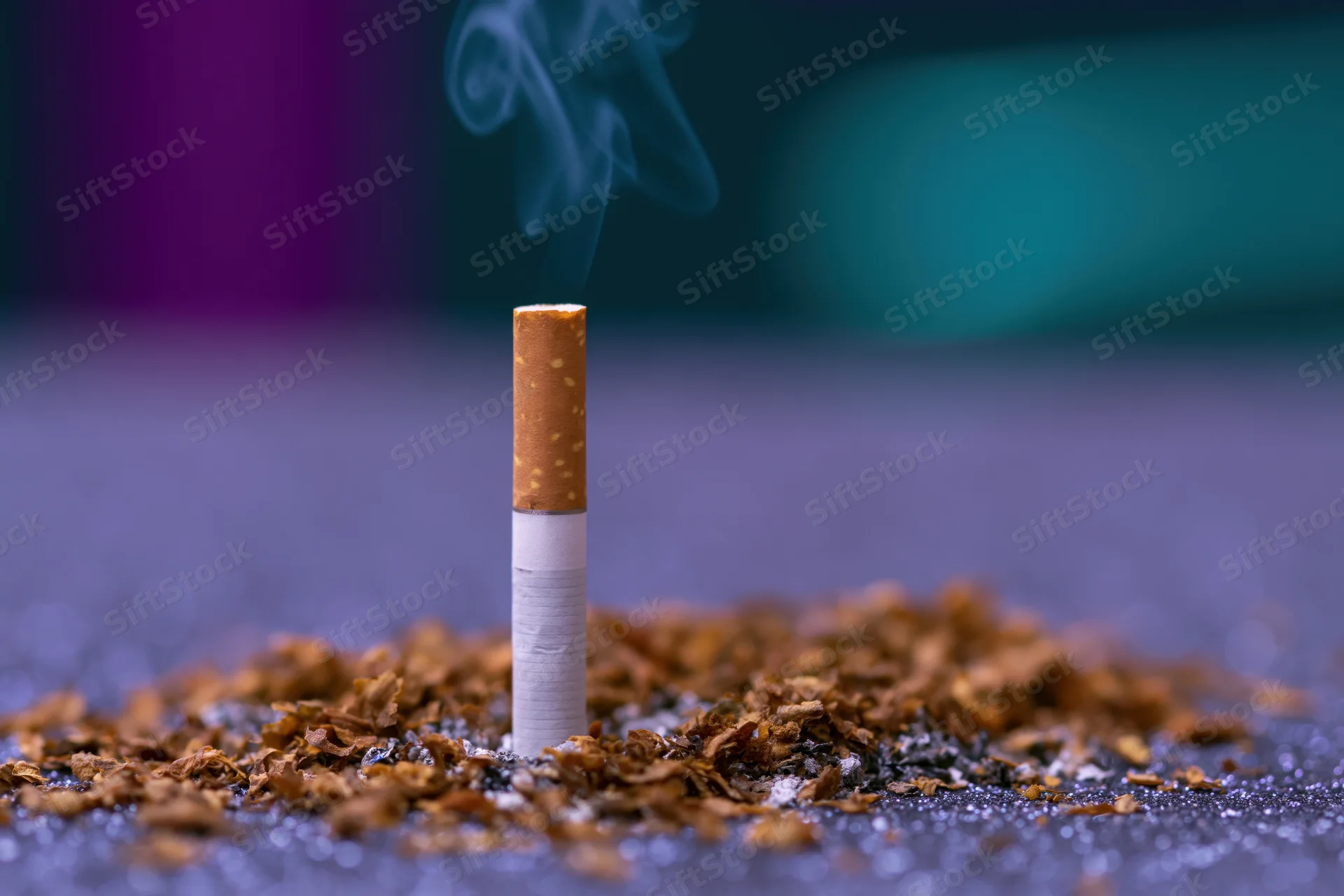 Single cigarette burning upright on glittery surface with smoke rising and ash scattered around