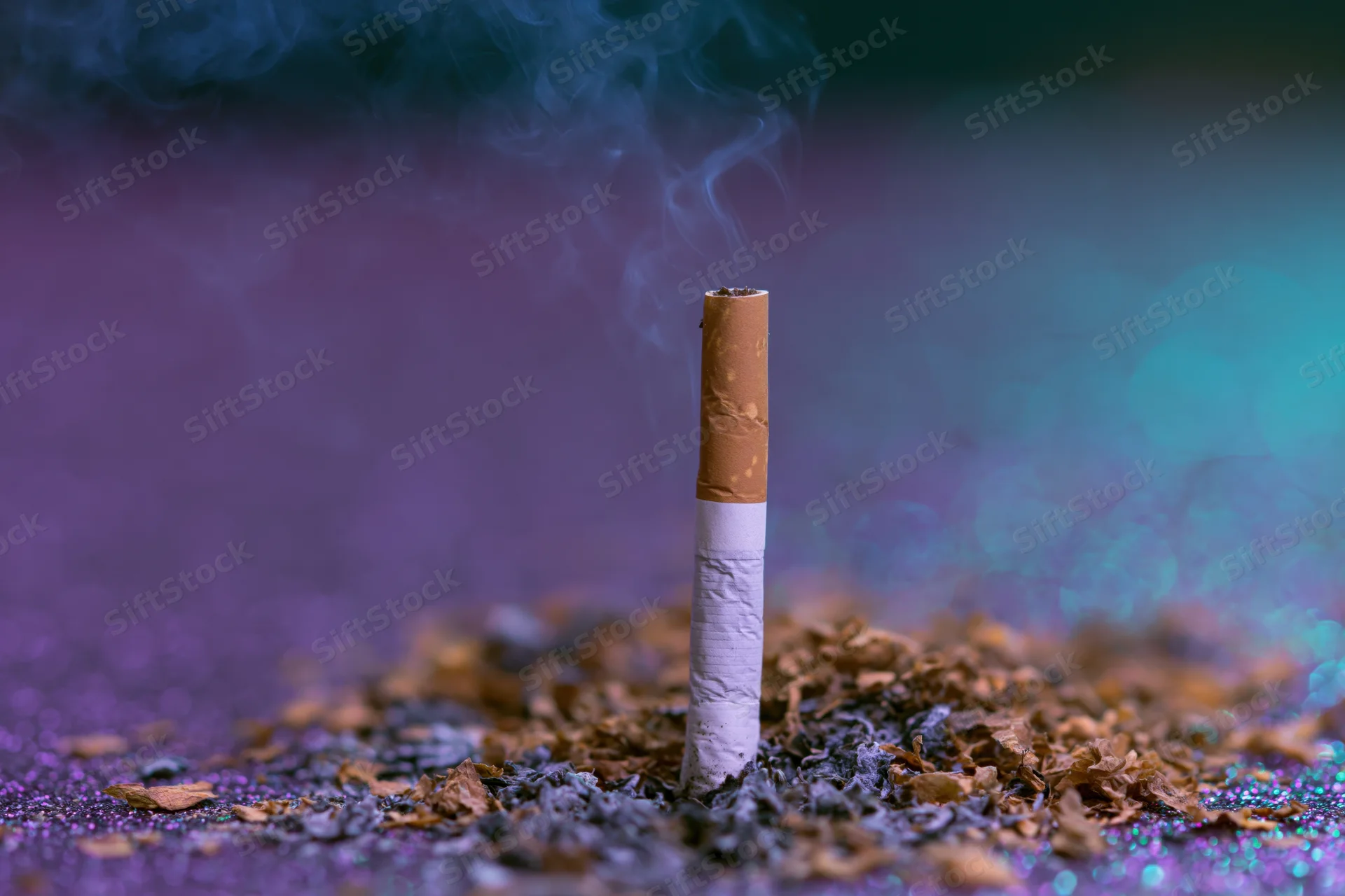 Single cigarette standing upright on glittery surface with smoke rising and ash scattered around