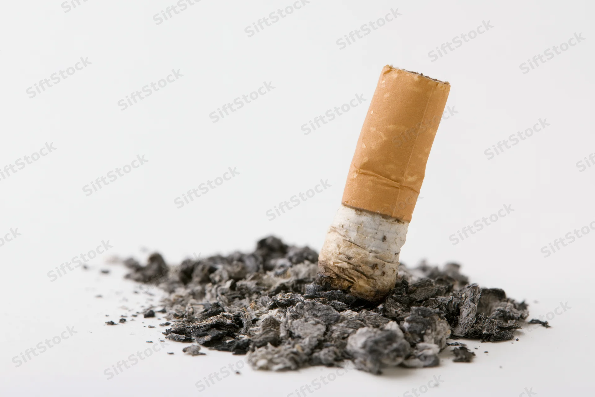 Extinguished cigarette butt standing upright in ash on white background