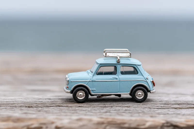 Small blue vintage toy car with luggage rack on wooden surface