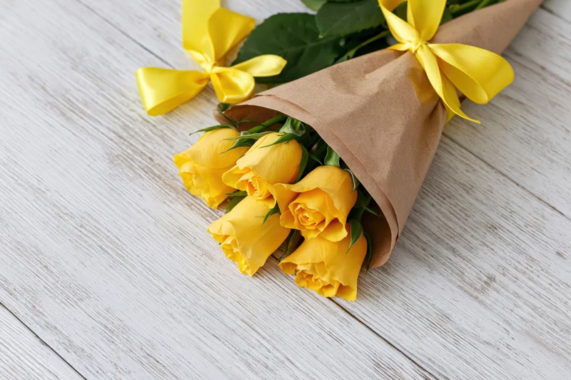 Bouquet of yellow roses wrapped in a cone of brown kraft paper