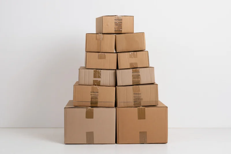 Pyramid-shaped stack of cardboard shipping boxes arranged on a white surface