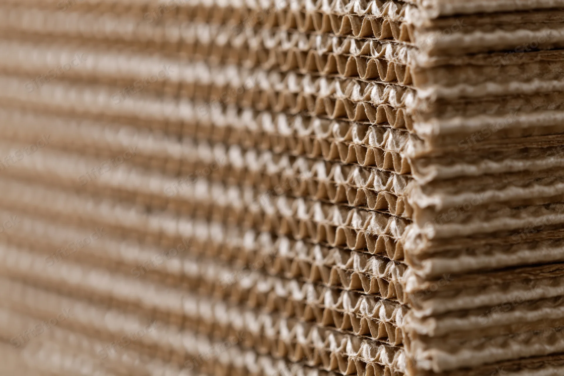 Tall stack of corrugated cardboard sheets arranged vertically with visible fluting and layered edges