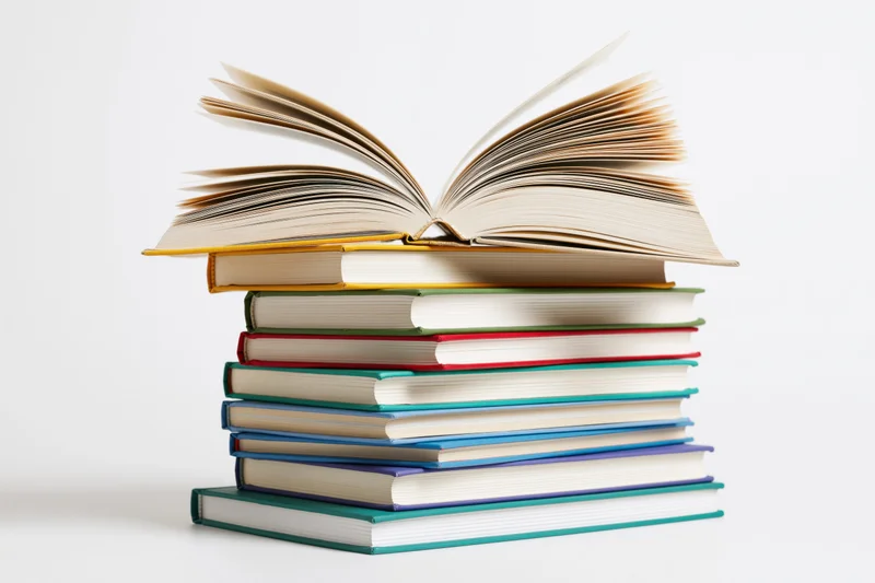 Stack of colorful hardcover books with one open on top against white background