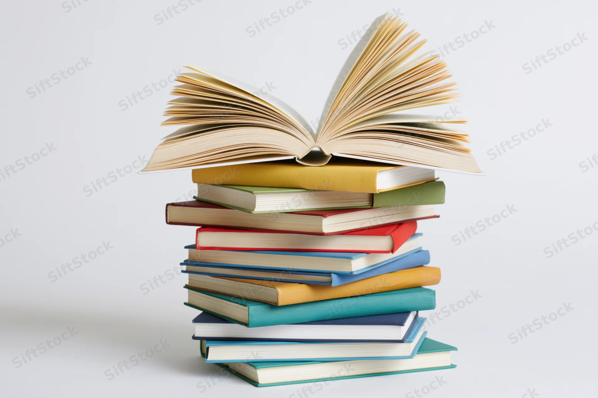 Tall stack of colorful hardcover books with one open on top, isolated on white background
