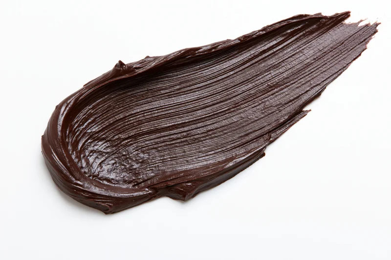 Thick dark chocolate spread swiped across a clean white surface