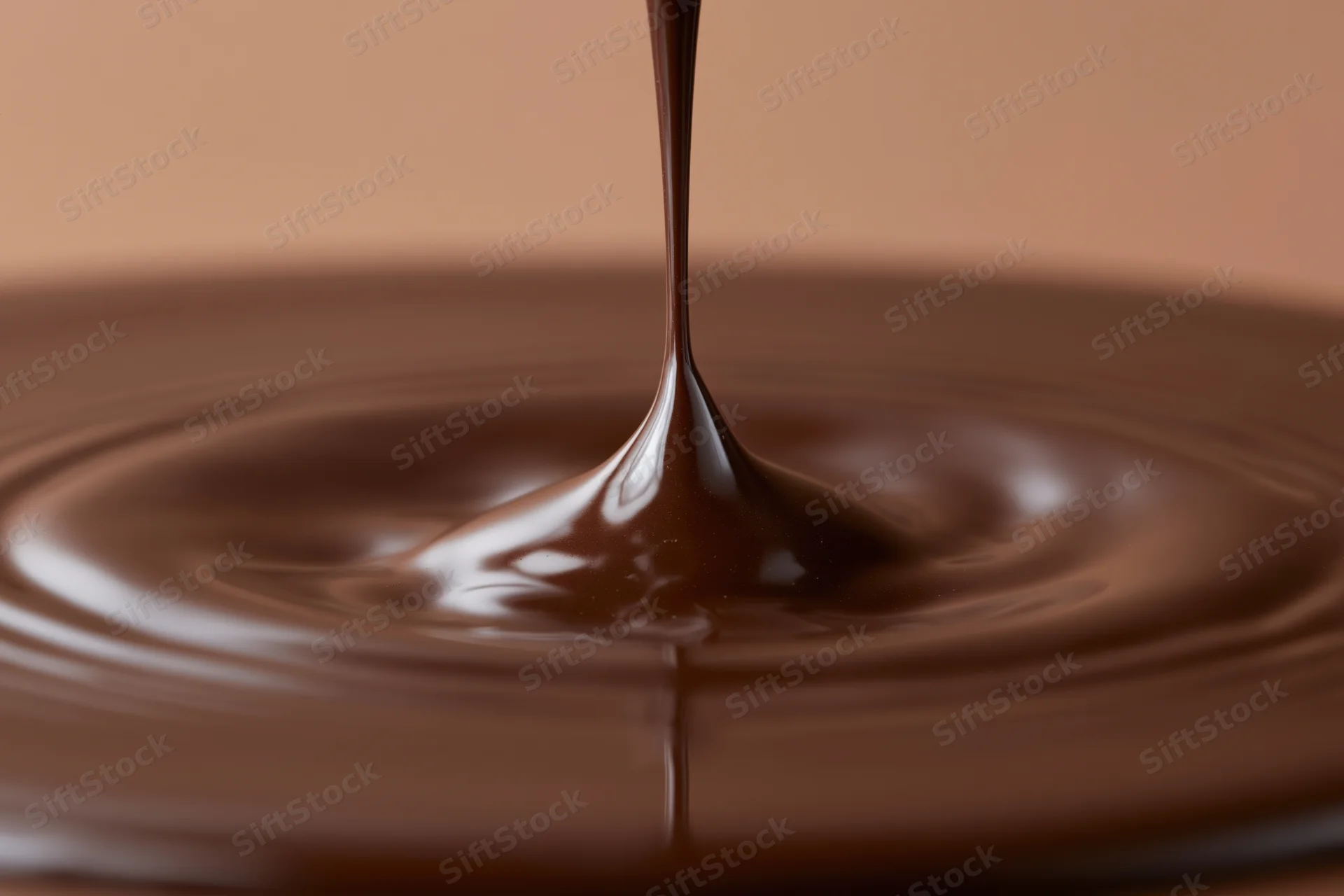 Dark chocolate pouring into a pool creating ripples on a smooth surface