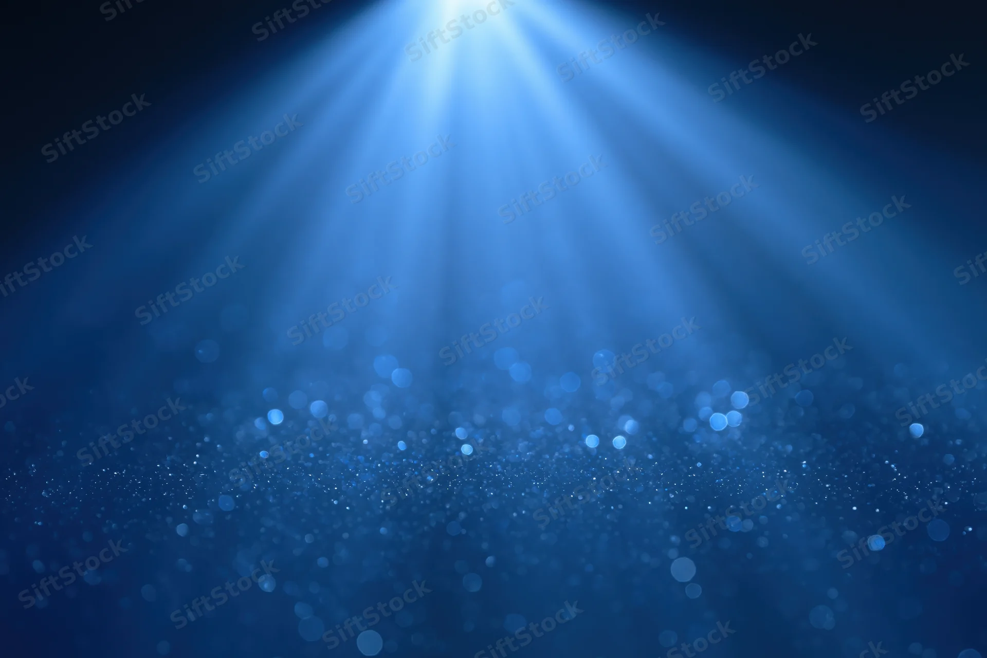 Blue light burst radiating upward from center with sparkling particles and bokeh effect in dark background