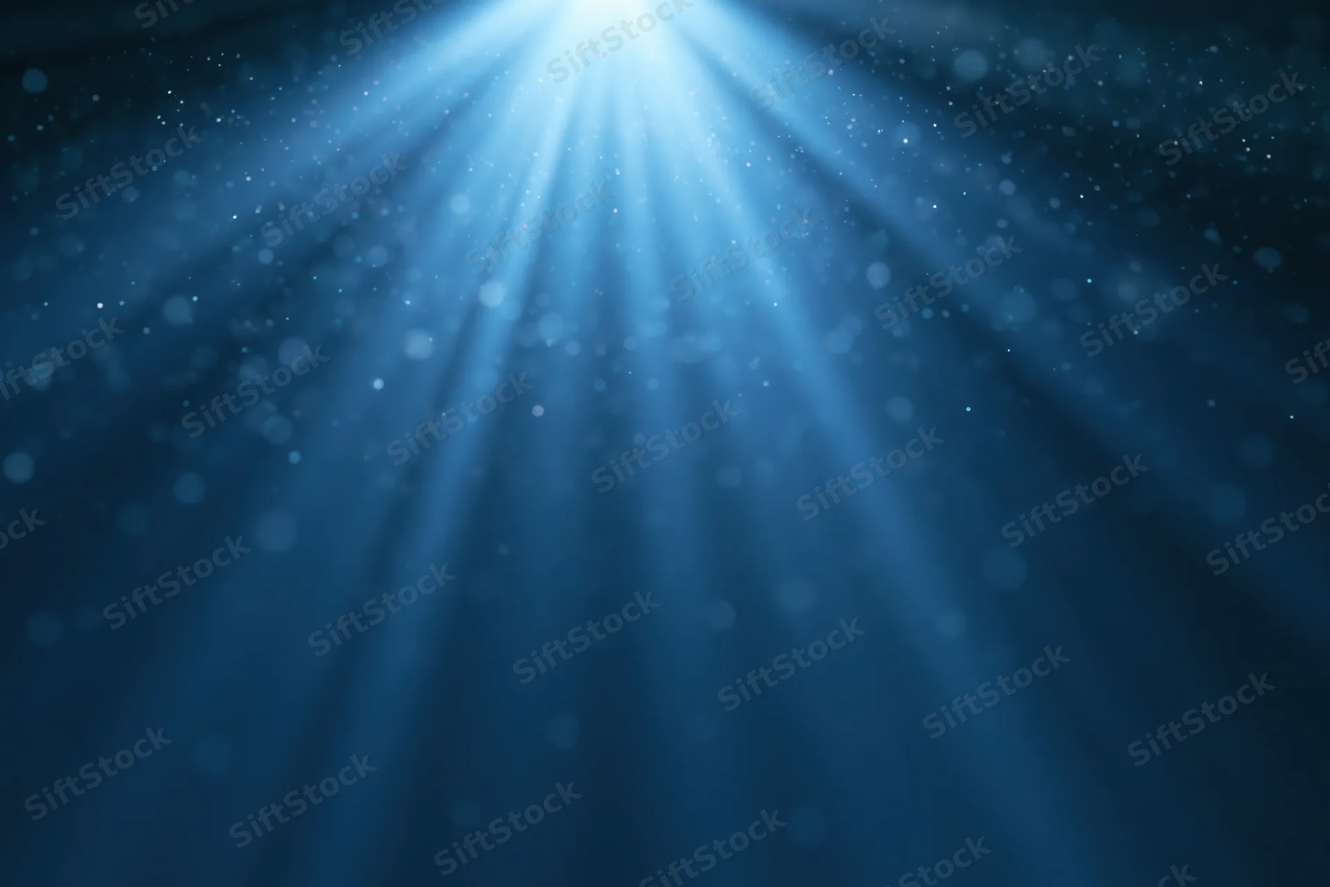 Blue light burst radiating upward from a central point in a dark abstract background with bokeh particles