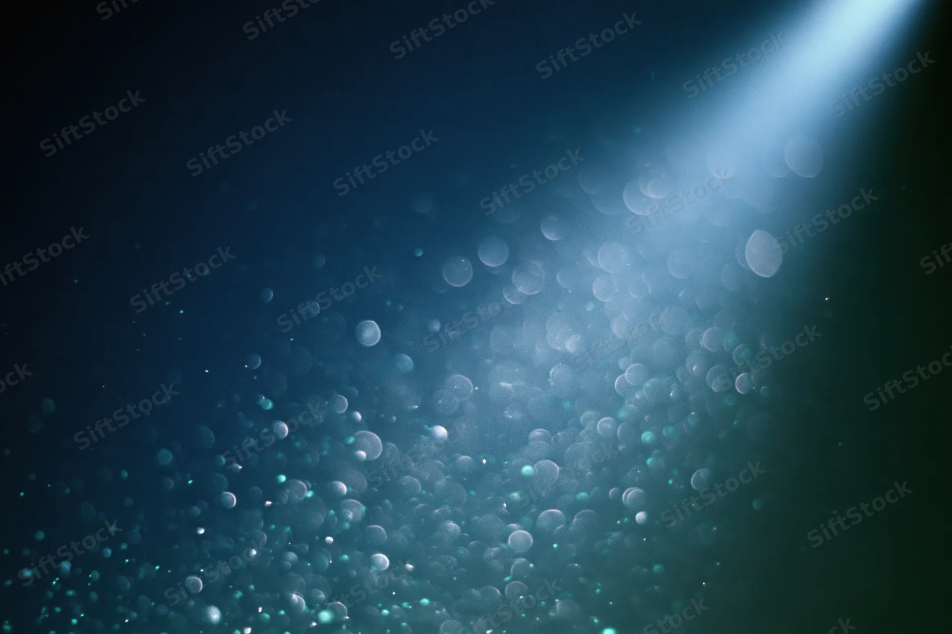 Floating out-of-focus light particles in dark blue abstract background with soft glow and bokeh effect
