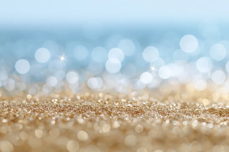Abstract defocused bokeh background with scattered light orbs and glittery gold surface