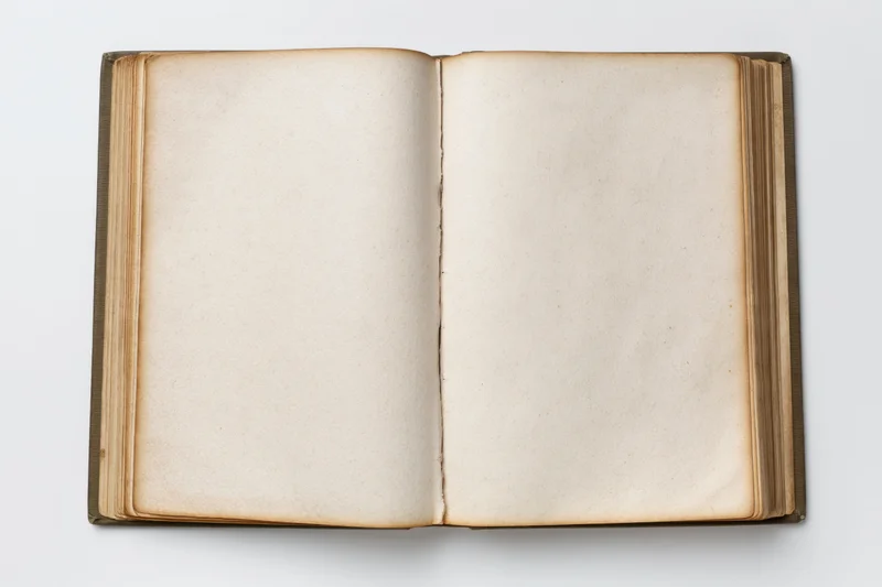 Open hardcover book with blank aged pages lying flat on white surface