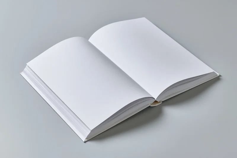 Open hardcover book with blank white pages lying flat on gray surface