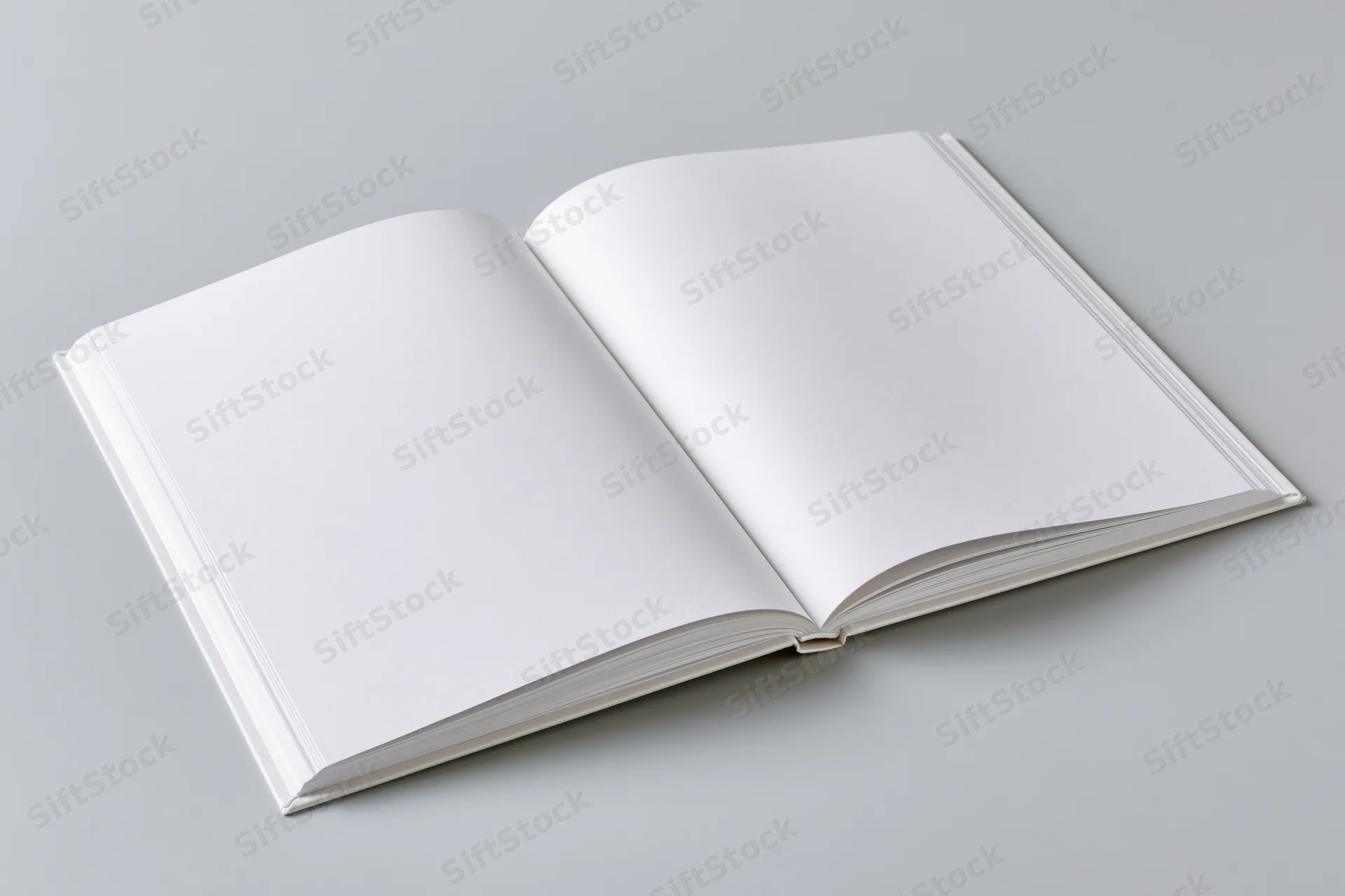 Open hardcover book with blank white pages lying flat on gray surface