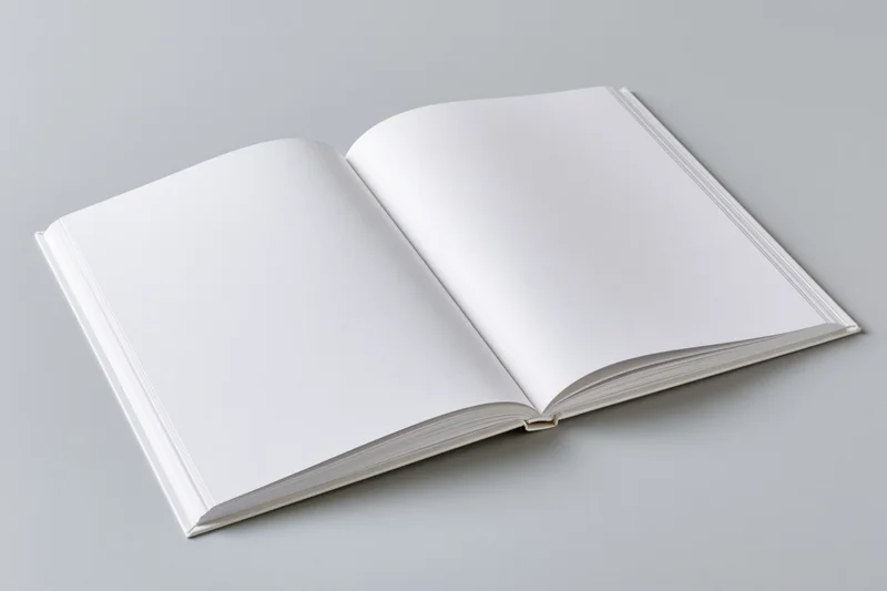 Open hardcover book with blank white pages lying flat on gray surface