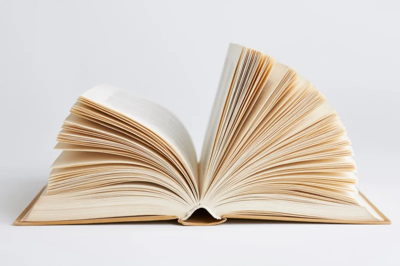 Open hardcover book with pages fanned out and curved spine on white background