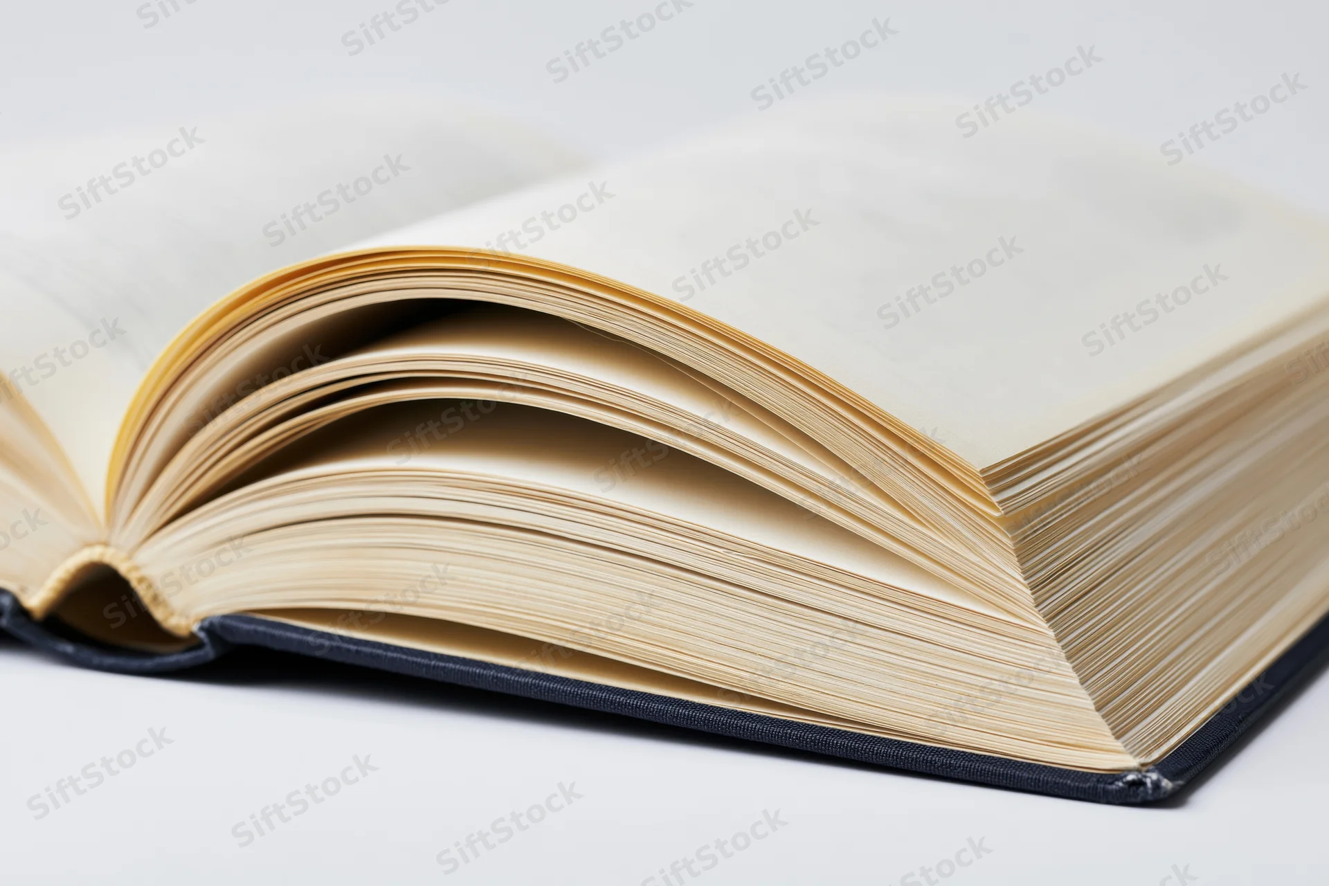 Open hardcover book with pages spread wide on white surface
