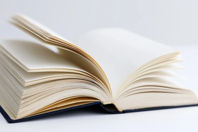 Open hardcover book with pages spread wide on white surface
