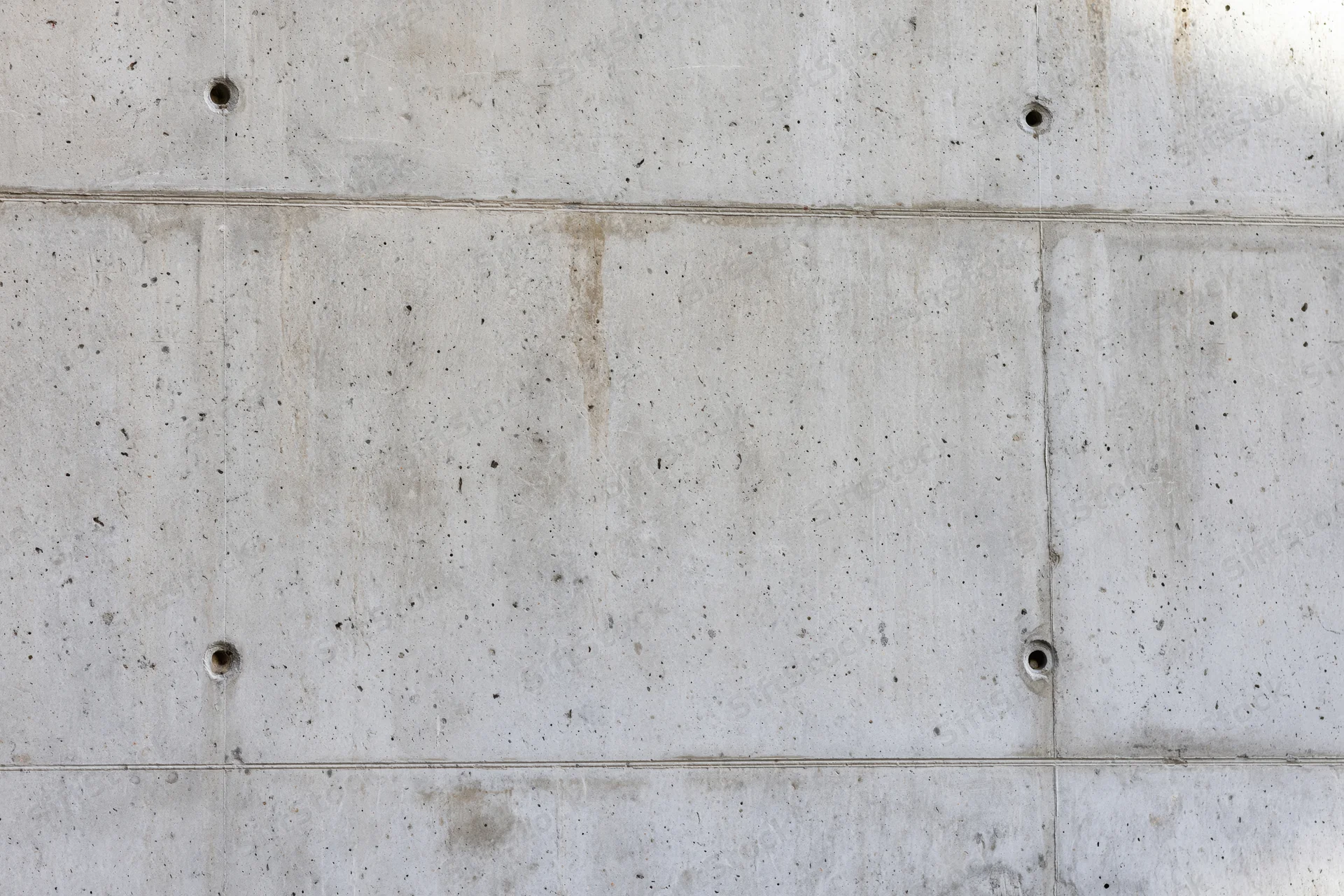 Bare concrete wall with formwork panel grid lines and small holes
