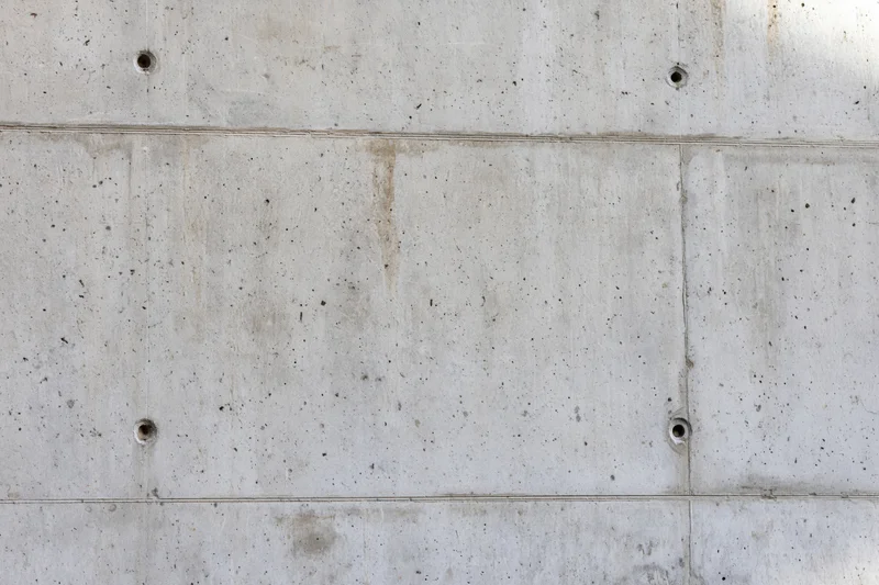 Bare concrete wall with formwork panel grid lines and small holes