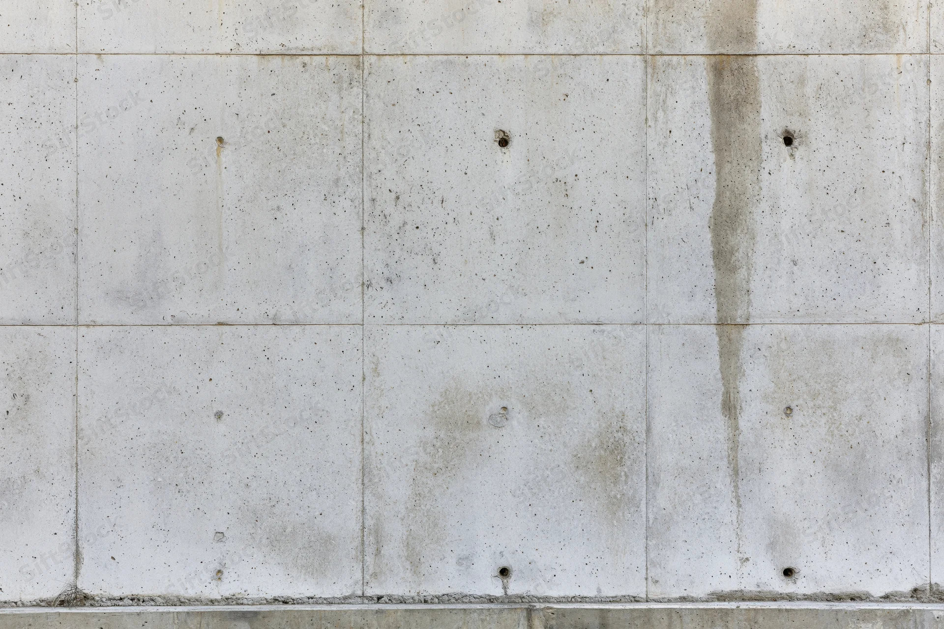 Bare concrete wall with formwork grid lines and small holes, exterior surface of a building under construction
