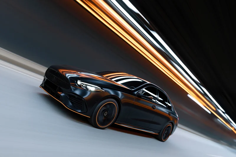 Black luxury sedan with orange accent trim speeding through a tunnel with light streaks in motion blur