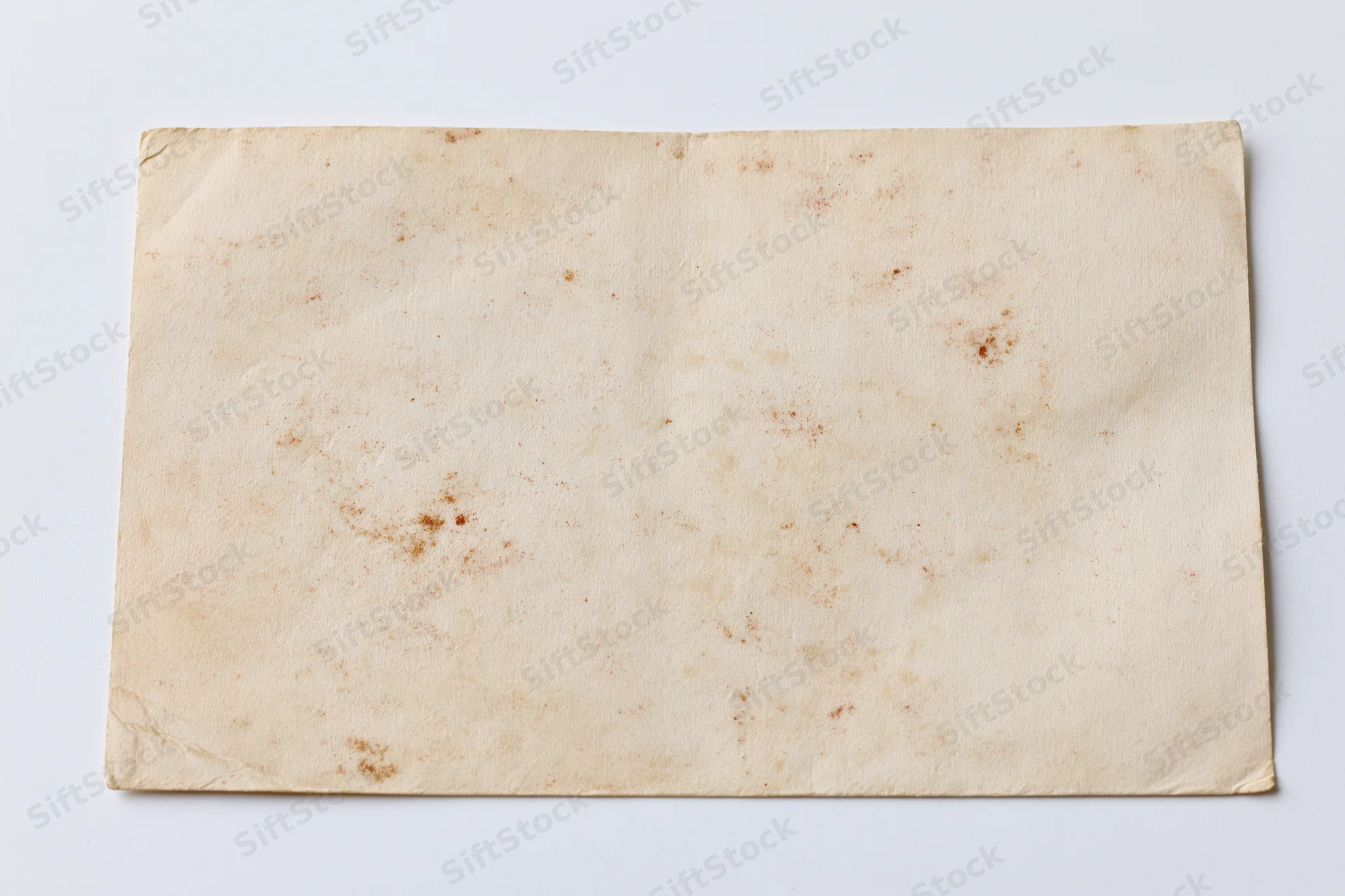 Blank vintage postcard lying flat on white background photographed straight-on
