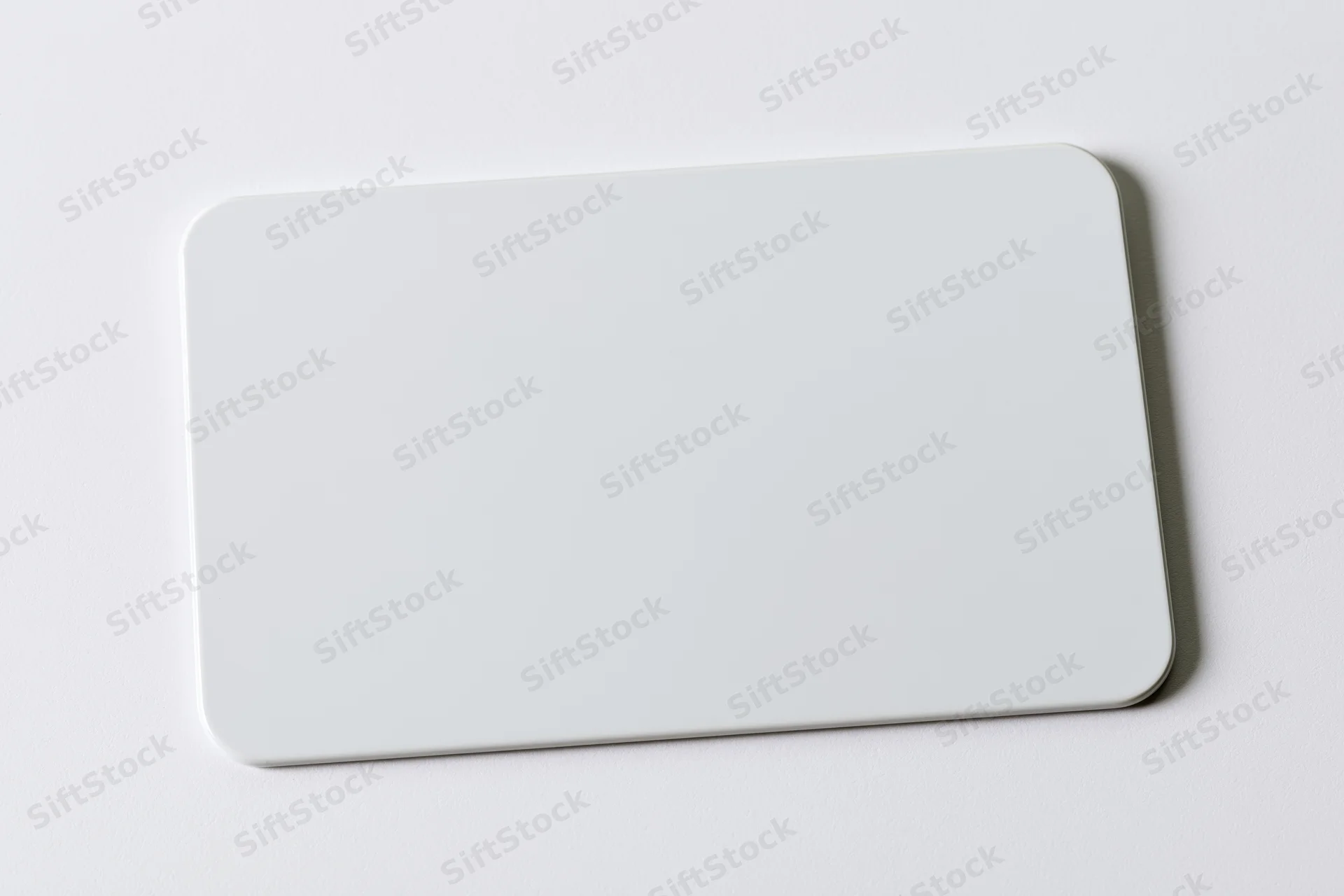 Blank white plastic card with rounded corners lying flat on a white surface