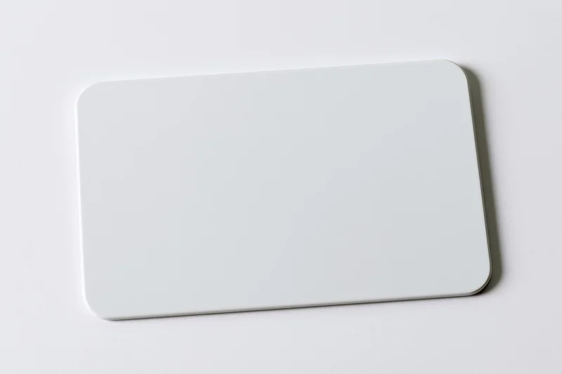 Blank white plastic card with rounded corners lying flat on a white surface