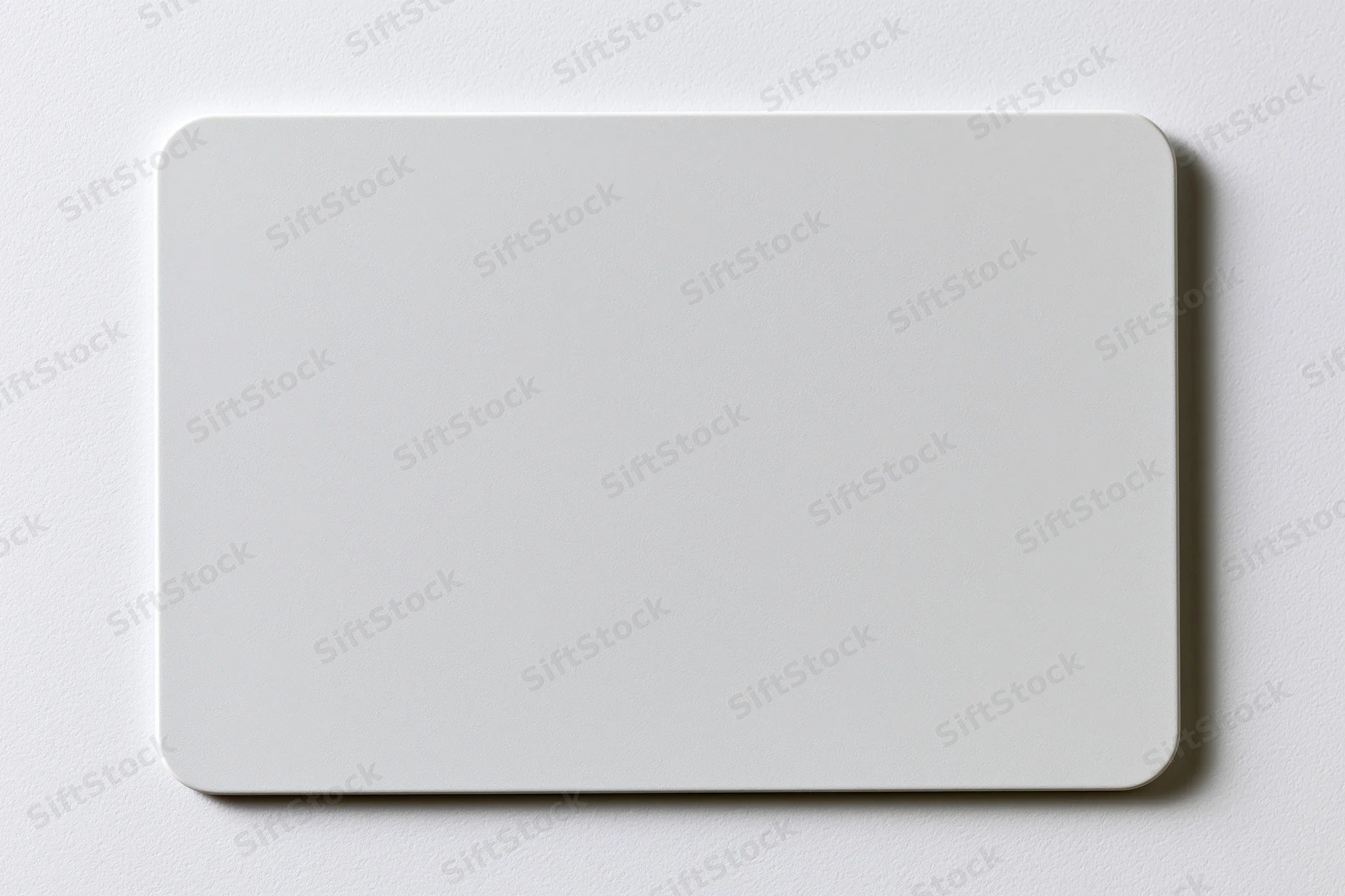 Blank white plastic card with rounded corners lying flat on a smooth surface