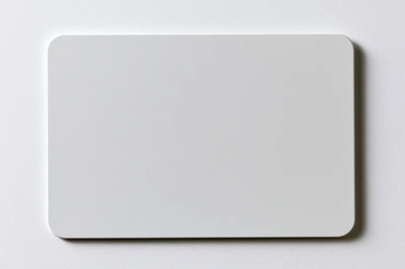 Blank white plastic card with rounded corners lying flat on a smooth surface