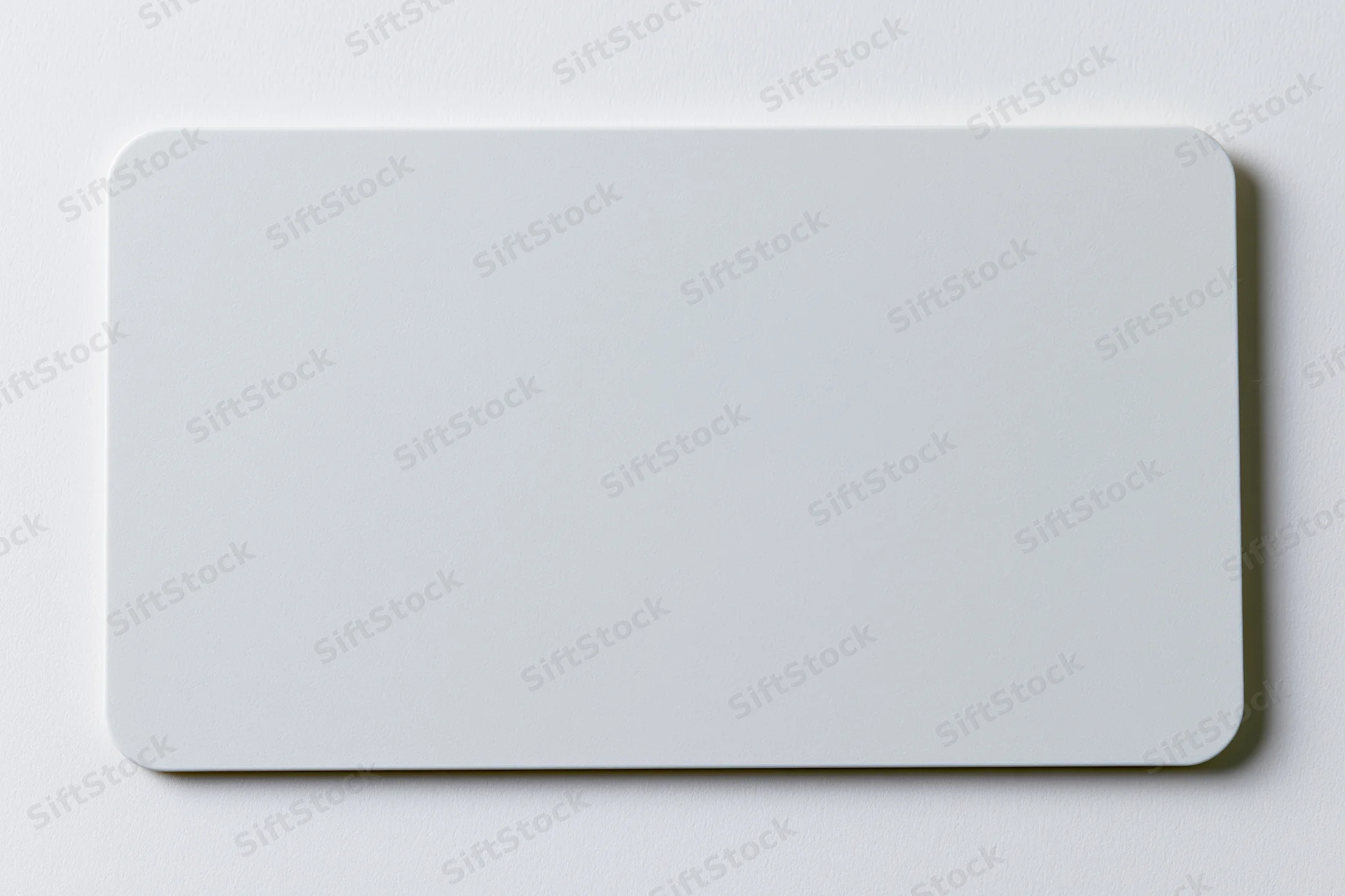 Blank white plastic card with rounded corners lying flat on a smooth surface
