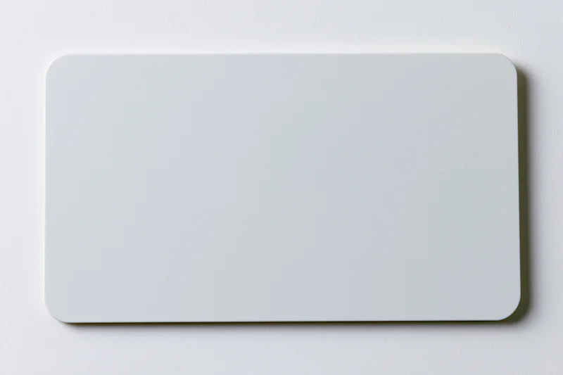 Blank white plastic card with rounded corners lying flat on a smooth surface