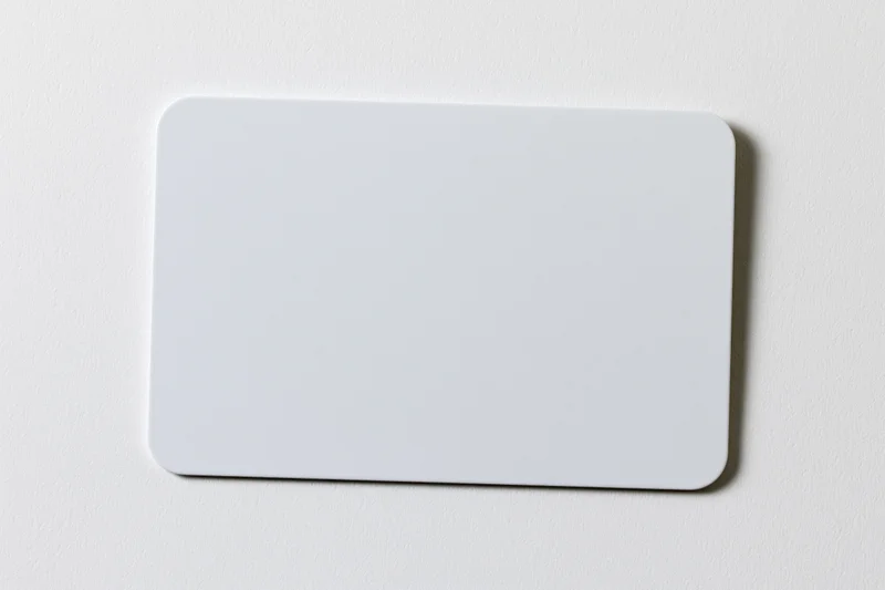 Blank white plastic card with rounded corners lying flat on a smooth white surface