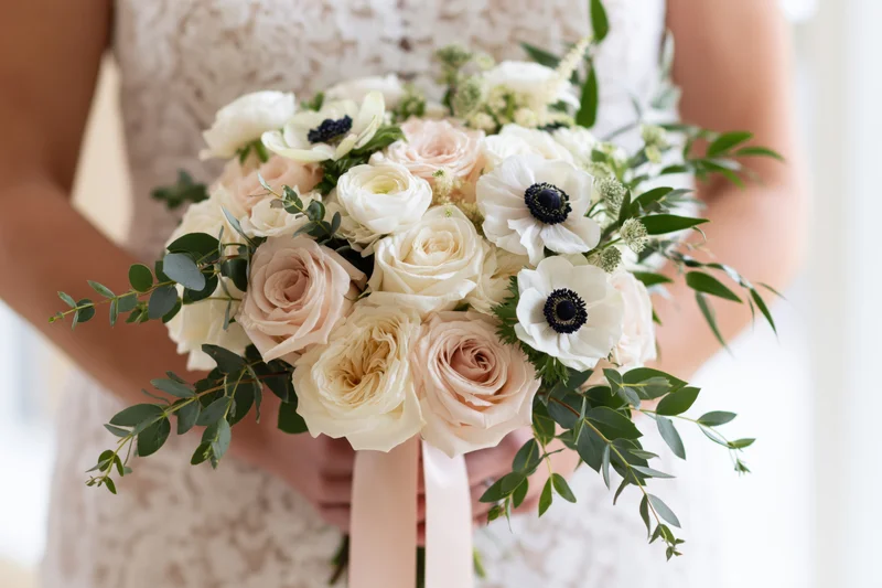 Bride holding a loose floral bouquet of roses and anemones with eucalyptus greenery