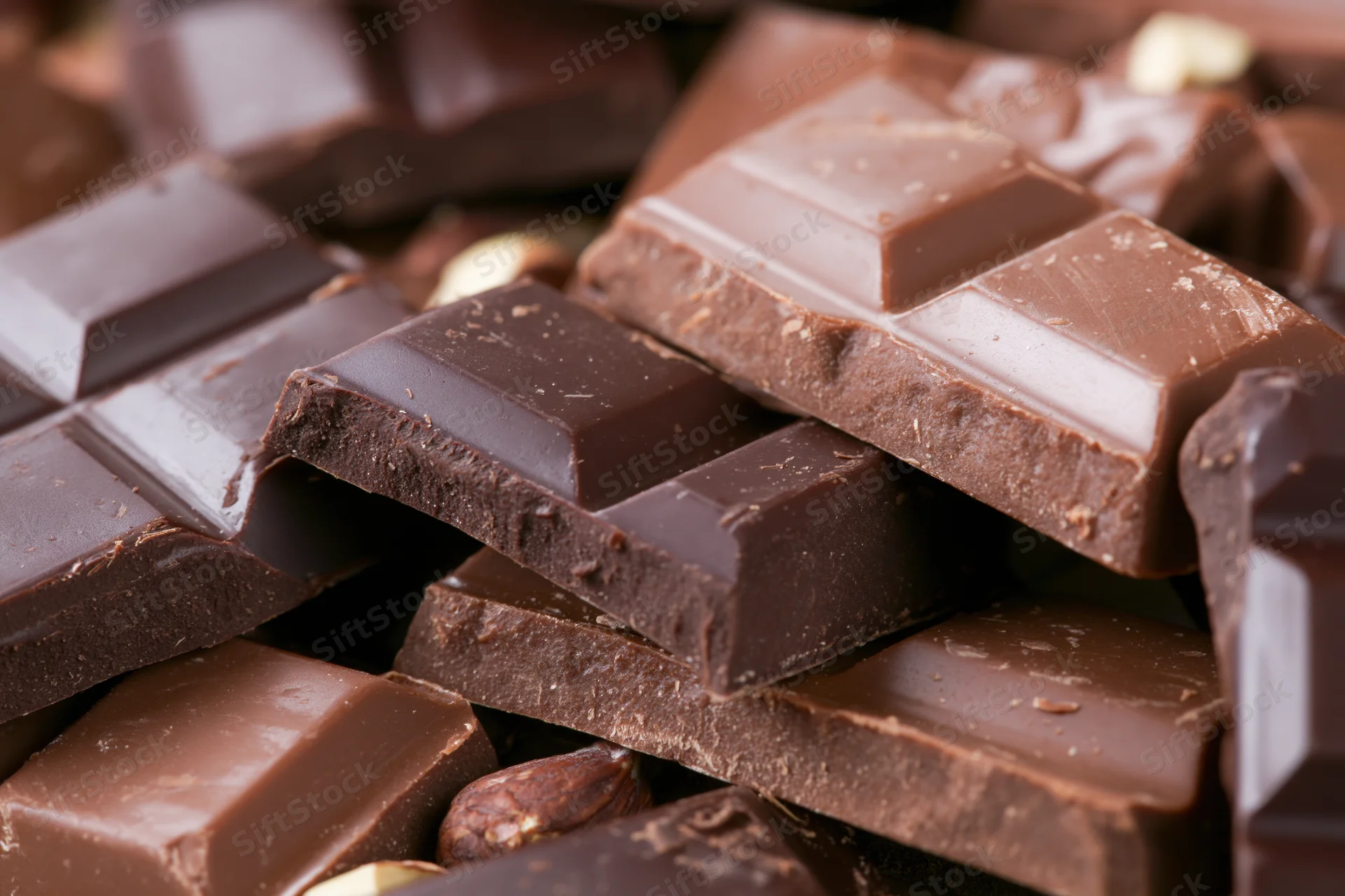Broken dark and milk chocolate bars stacked and scattered in closeup view