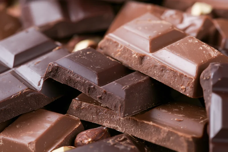 Broken dark and milk chocolate bars stacked and scattered in closeup view