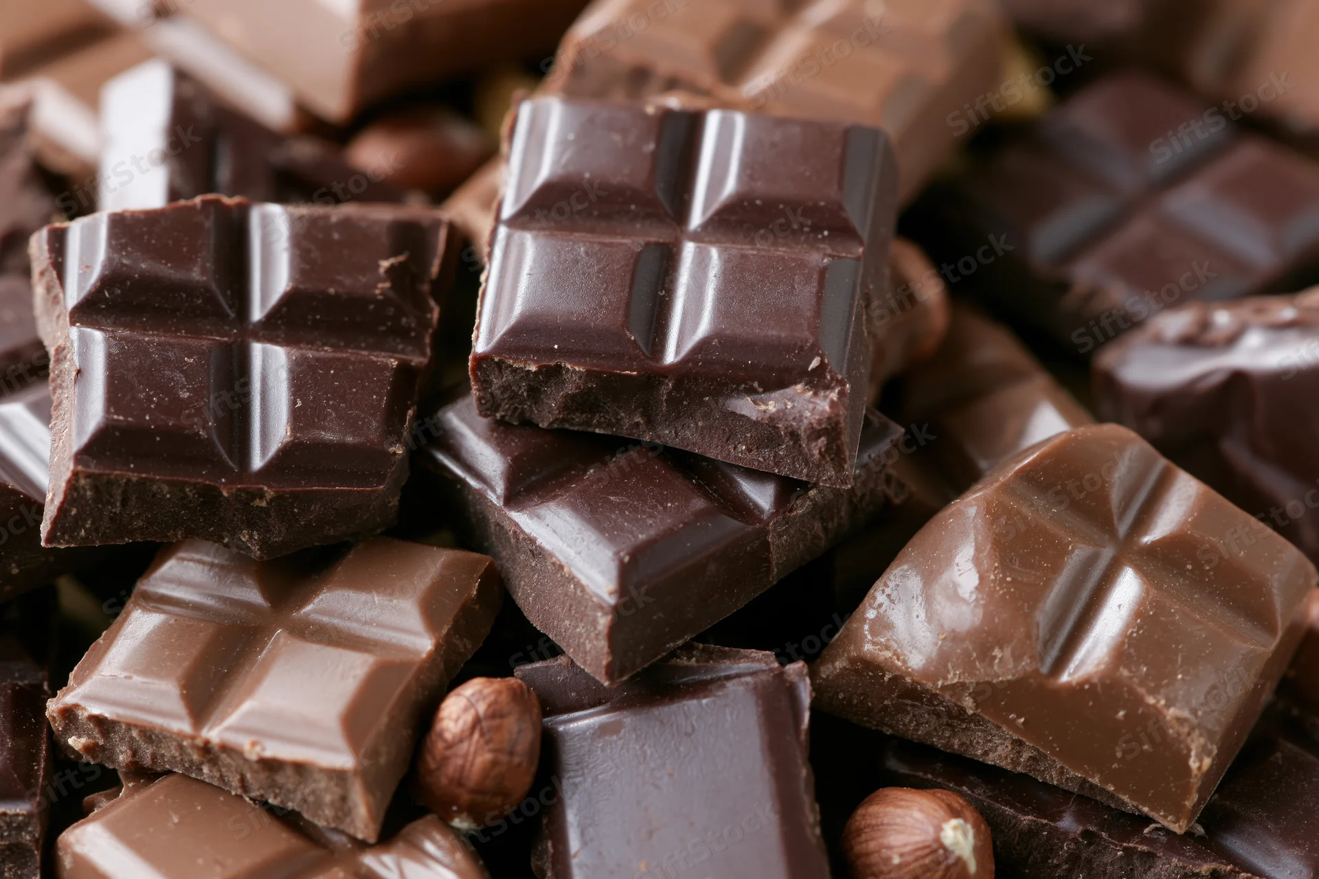 Broken dark and milk chocolate bars scattered and stacked in closeup view
