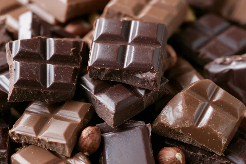 Broken dark and milk chocolate bars scattered and stacked in closeup view
