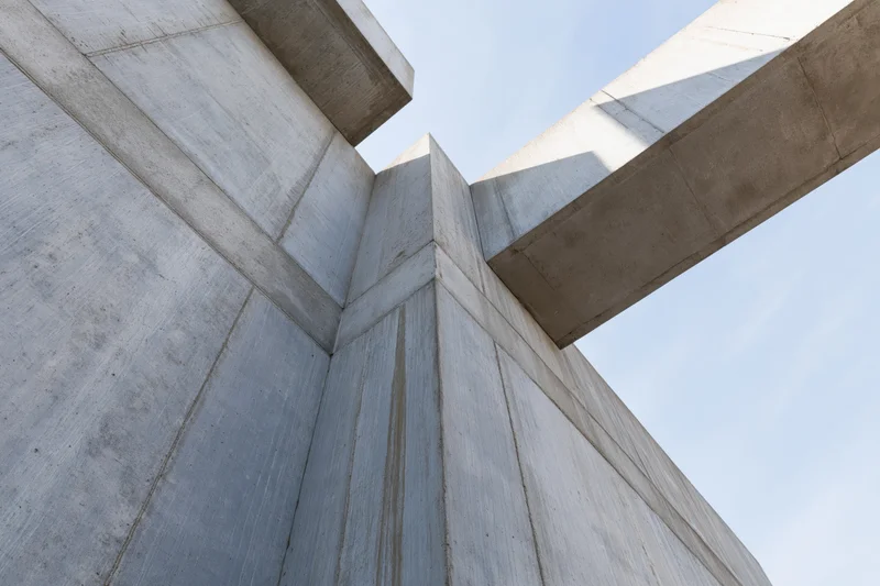 Brutalist concrete structure viewed from low angle showing corner and beams against sky