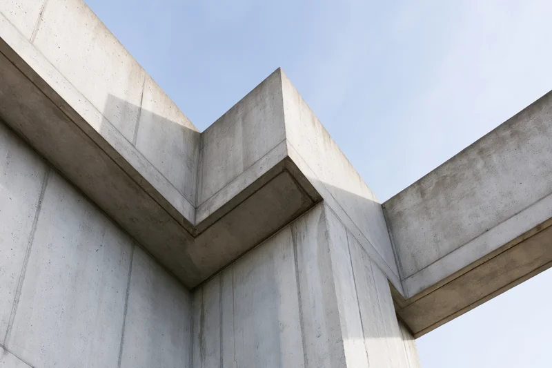 Brutalist concrete building corner viewed from low angle against blue sky