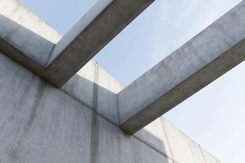 Low-angle view of brutalist concrete structure with intersecting beams and walls against sky