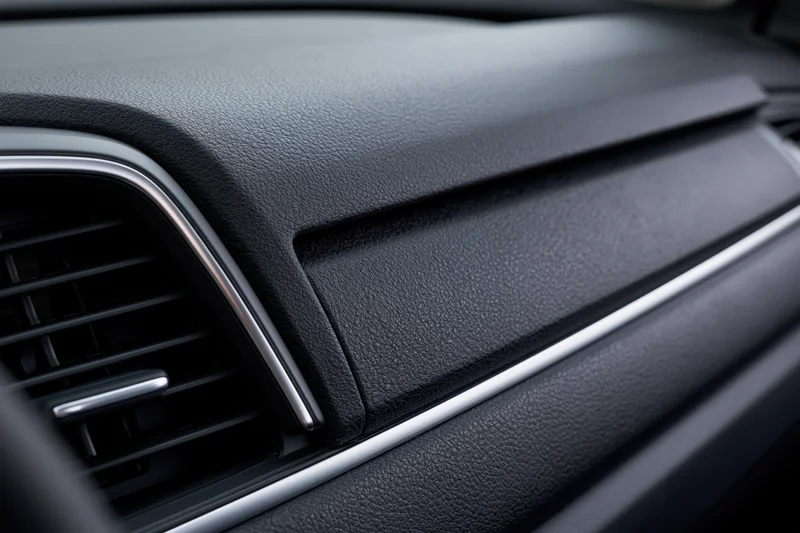 Closeup of car dashboard with glove box panel and air vent trim