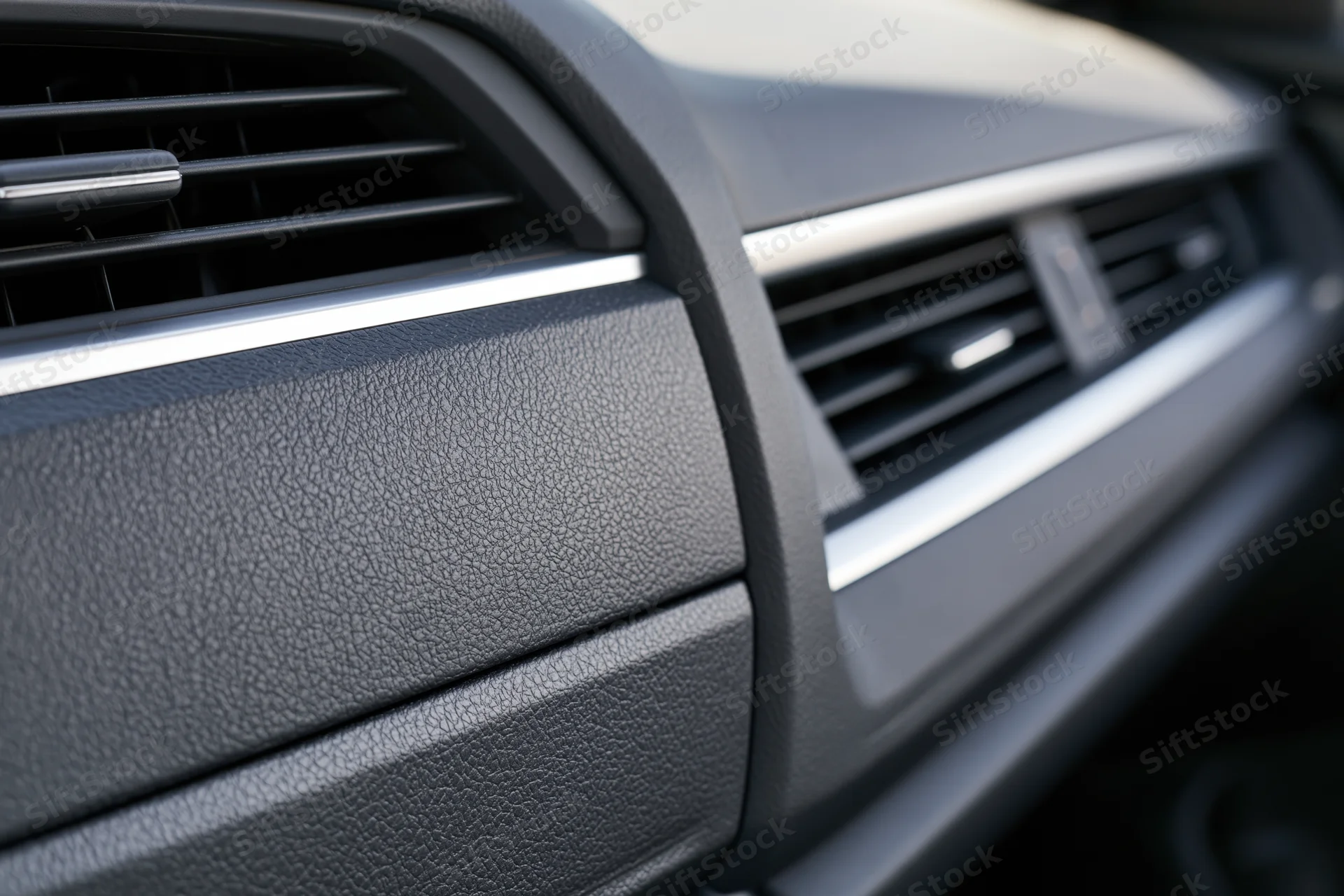 Closeup of car dashboard and glove box panel showing air vents and textured trim