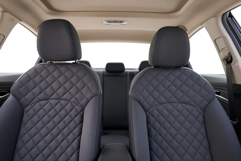 Rear view of car interior showing front seats with quilted black upholstery and beige ceiling