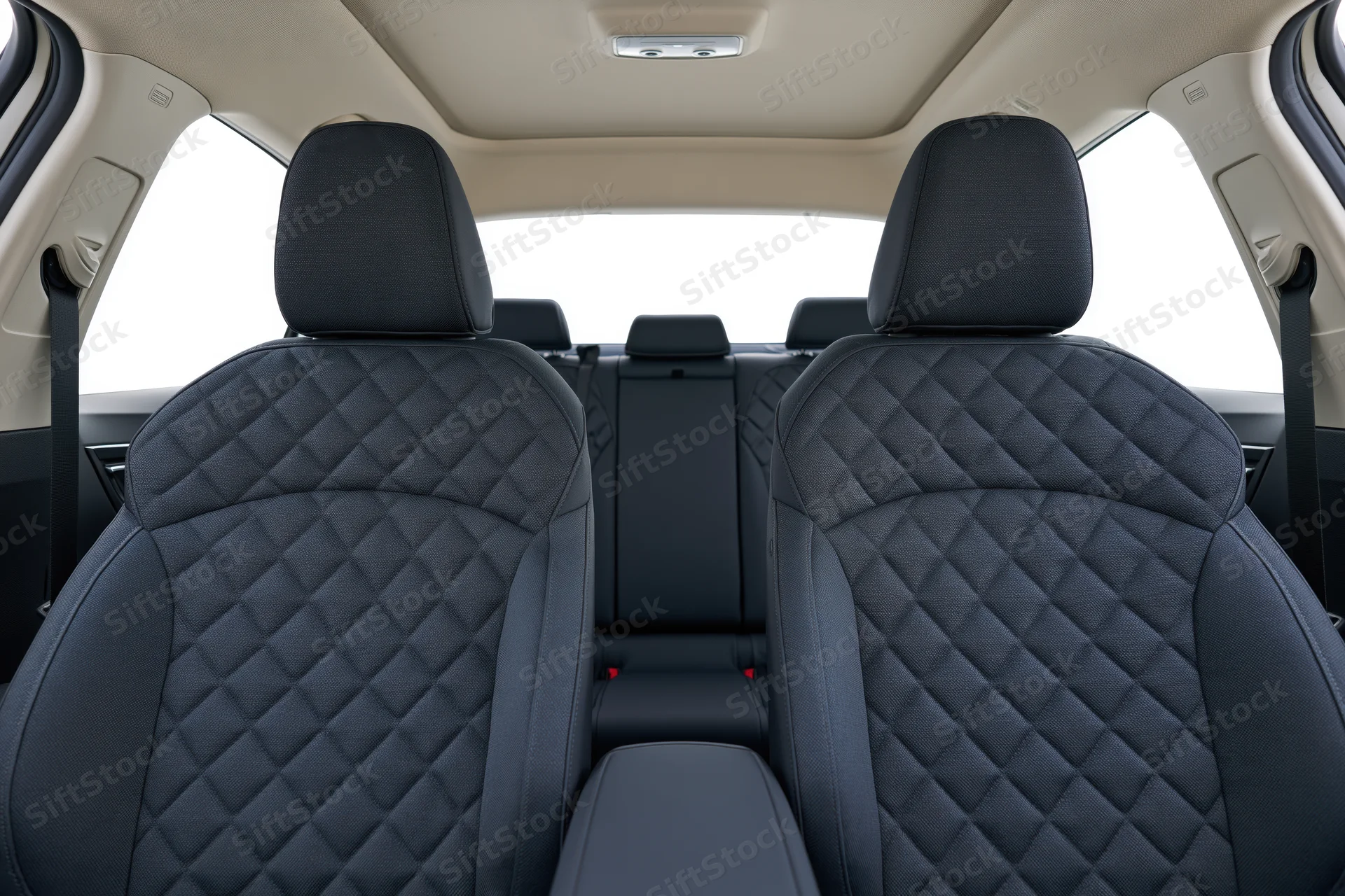 Rear view of black quilted leather seats in a car interior with beige ceiling and headrests