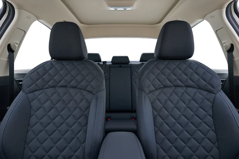 Rear view of black quilted leather seats in a car interior with beige ceiling and headrests