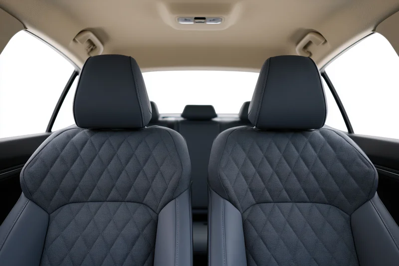 Rear view of car interior showing front seats with quilted upholstery and beige ceiling